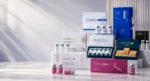 Luxury aesthetic pharmacy banner featuring AKRADEX skincare and mesotherapy products displayed on elegant white marble podiums. LENNEA Booster, MESOTEN, REVACOLL, MESOTEN Eyes, MESOTEN Pure Skin, ElastiFill, and Combo DNA products are professionally arranged on the right side against a clean, modern clinic-inspired background with soft natural lighting and empty space on the left for website text and call-to-action content.