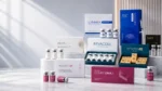 Luxury aesthetic pharmacy banner featuring AKRADEX skincare and mesotherapy products displayed on elegant white marble podiums. LENNEA Booster, MESOTEN, REVACOLL, MESOTEN Eyes, MESOTEN Pure Skin, ElastiFill, and Combo DNA products are professionally arranged on the right side against a clean, modern clinic-inspired background with soft natural lighting and empty space on the left for website text and call-to-action content.